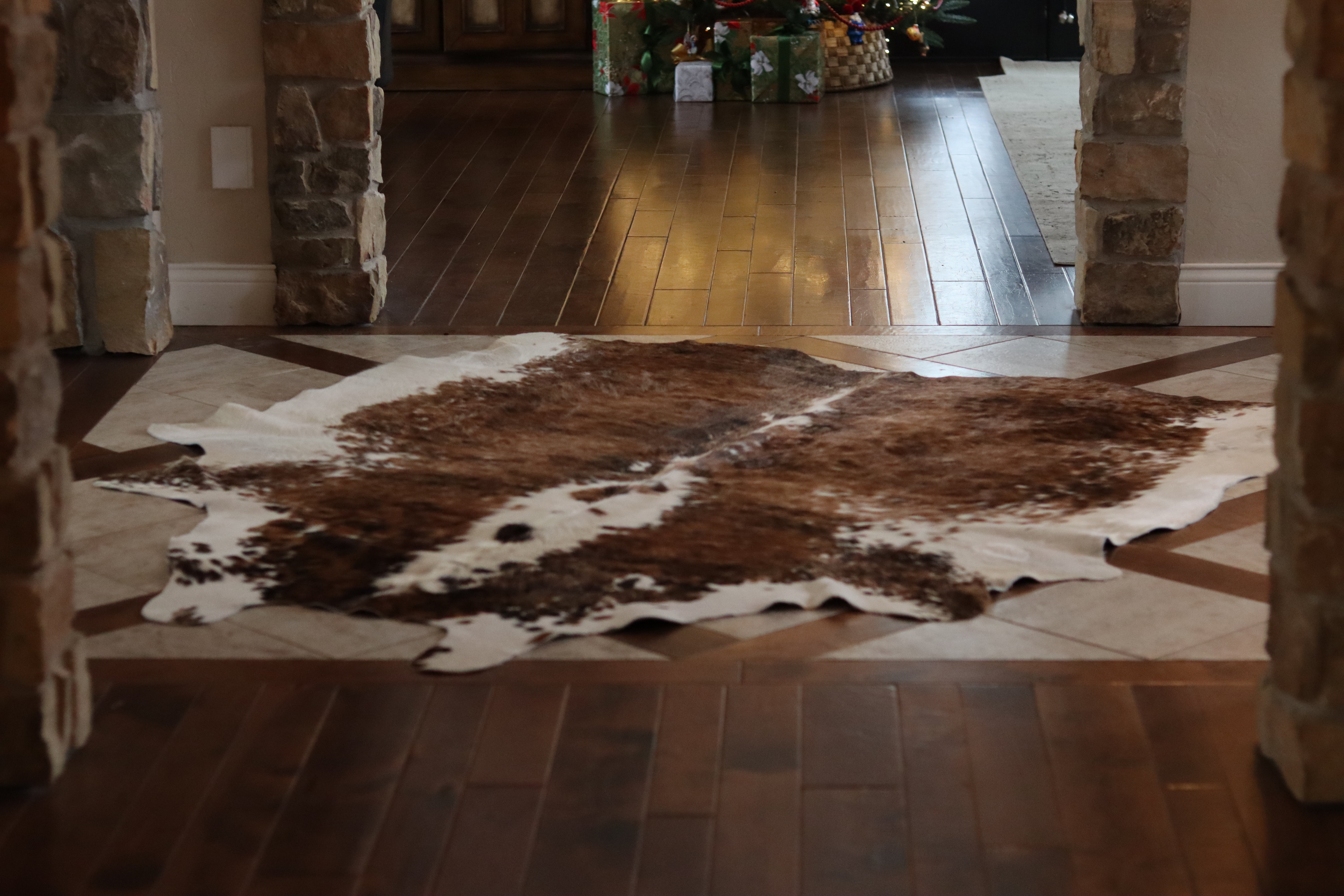 
    Brown and white cowhide rug on a wooden floor in a room with stone walls.


  